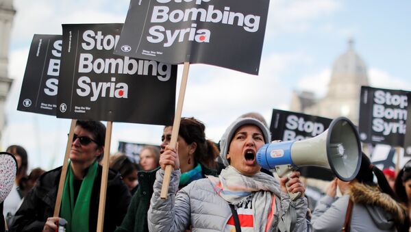 Protestors carry placards as they demonstrate against the UK's military involvement in Syria, outside the Houses of Parliament in central London - Sputnik International