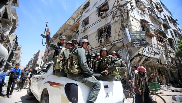 Members of the Syrian police hold their weapons as they sit on a back of a truck at the city of Douma, Damascus, Syria April 16, 2018 - Sputnik International