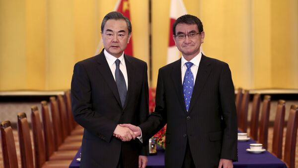 Japanese Foreign Minister Taro Kono, right, and his Chinese counterpart Wang Yi, left, shake hands ahead of their meeting in Tokyo - Sputnik International