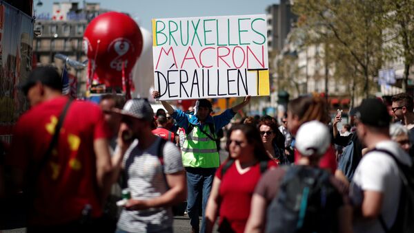A man holds a placard reading Brussels Macron derailed during a demonstration against the French government's reform plans in Paris as part of a national day of protest, France, April 19, 2018 - Sputnik International