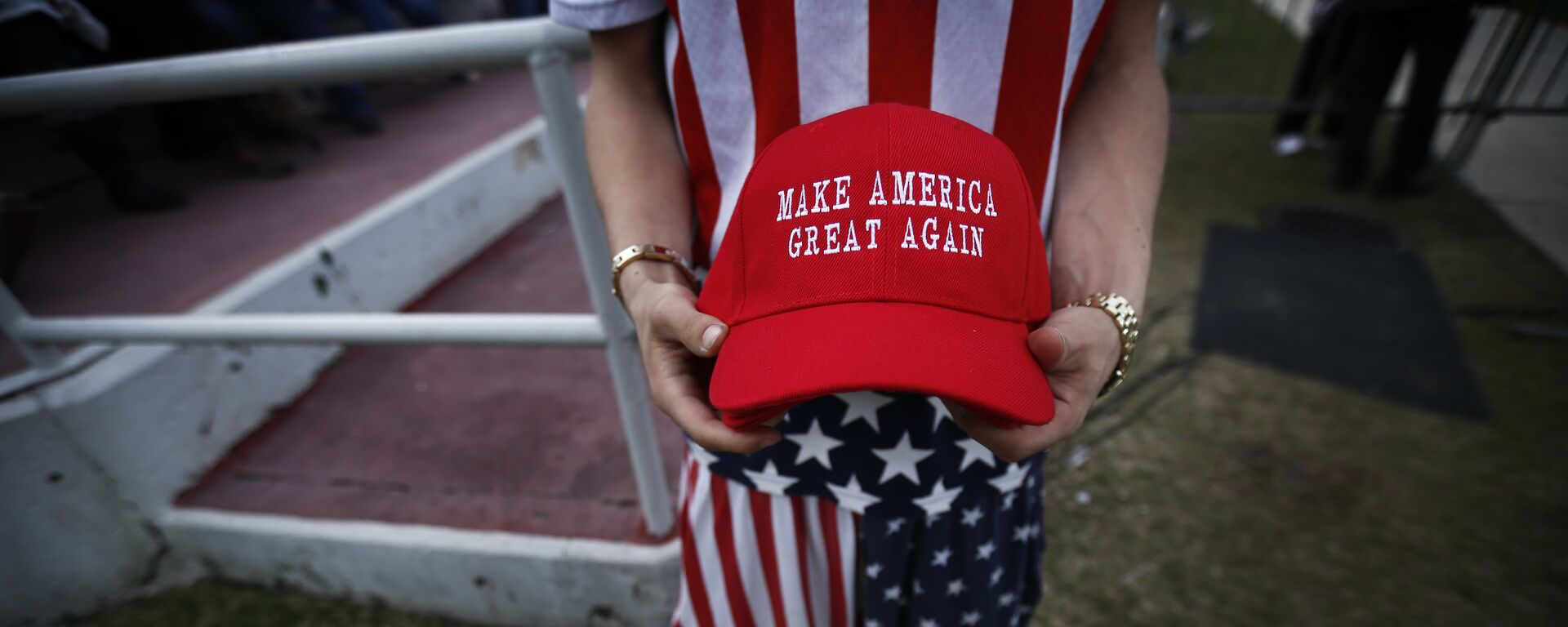 A man dressed in American flag clothes holds Make America Great Again hats. - Sputnik International, 1920, 28.08.2022