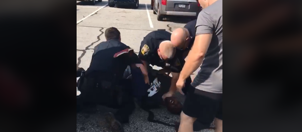 Former NFL player Desmond Marrow is pinned to the ground by three officers of the Henry County Police Department in Georgia as they arrest him. - Sputnik International