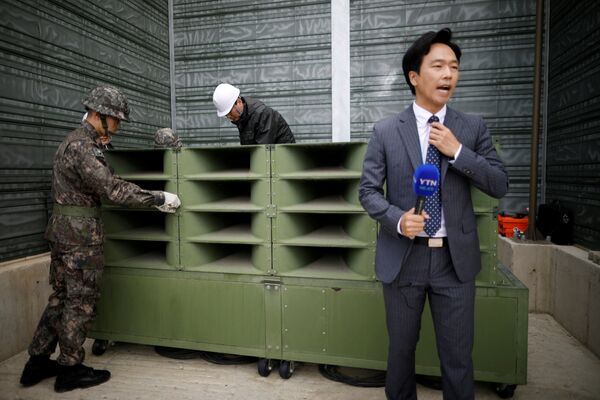 A reporter prepares a news report as South Korean soldiers dismantle loudspeakers that were set up for propaganda broadcasts near the demilitarized zone separating the two Koreas in Paju, South Korea, May 1, 2018. - Sputnik International