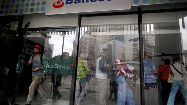 A customer leaves a Banesco's bank branch as other wait in line, in Caracas, Venezuela, Friday, May 4, 2018 - Sputnik International