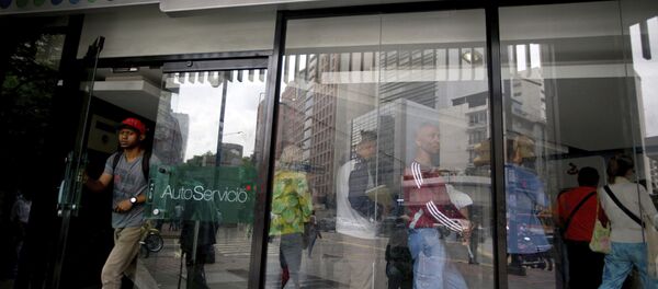 A customer leaves a Banesco's bank branch as other wait in line, in Caracas, Venezuela, Friday, May 4, 2018 - Sputnik International