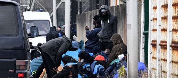 Migrants gather by the ringroad leading to the harbour on March 30, 2018 in Calais, near a police van patrolling (Rear L) Migrants gather by the ringroad leading to the harbour on March 30, 2018 in Calais, near a police van patrolling (Rear L) - Sputnik International