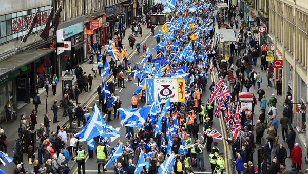 Anti-independence supporters wave Union Jack flags (R) as thousands of demonstrators carry Saltire flags, the national flag of Scotland, as they march in support of Scottish independence through the streets of Glasgow, on May 5, 2018 - Sputnik International