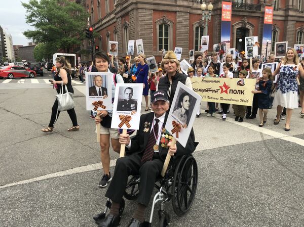 People walked from the White House to the WWII memorial while holding up photos of their relatives who had participated in the war, the only WWII veteran present at the event was heading the march. - Sputnik International