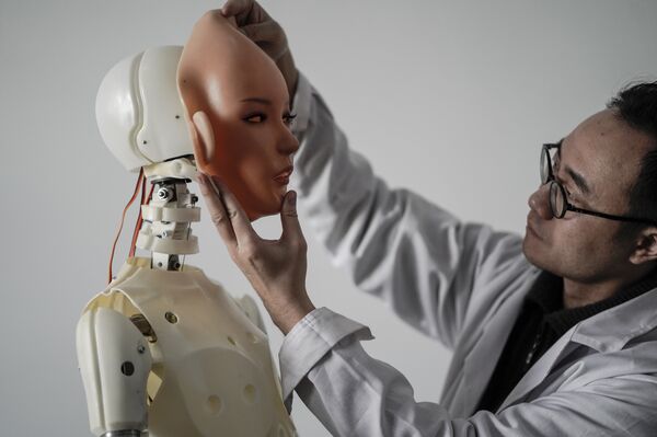 This photo taken on February 1, 2018 shows an engineer holding a silicon face against the head of a robot at a lab of a doll factory of EXDOLL, a firm based in the northeastern Chinese port city of Dalian This photo taken on February 1, 2018 shows an engineer holding a silicon face against the head of a robot at a lab of a doll factory of EXDOLL, a firm based in the northeastern Chinese port city of Dalian - Sputnik International