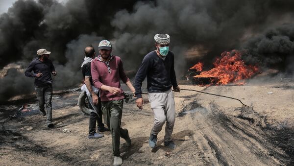 Palestinian protesters pull on a burning tire during clashes with Israeli forces on April 20, 2018, east of Khan Yunis, in the southern Gaza Strip during mass protests along the border of the Palestinian enclave, dubbed The Great March of Return, which has the backing of Gaza's Islamist rulers Hamas - Sputnik International