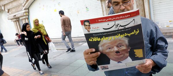 An Iranian man reads a copy of the daily newspaper 'Omid Javan' bearing a picture of US President Donald Trump with a headline that reads in Persian Crazy Trump and logical JCPOA (Joint Comprehensive Plan of Action), on October 14, 2017, in front of a kiosk in the capital Tehran An Iranian man reads a copy of the daily newspaper 'Omid Javan' bearing a picture of US President Donald Trump with a headline that reads in Persian Crazy Trump and logical JCPOA (Joint Comprehensive Plan of Action), on October 14, 2017, in front of a kiosk in the capital Tehran - Sputnik International