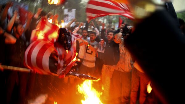 Iranian demonstrators burn representations of the U.S. flag during a protest in front of the former U.S. Embassy in response to President Donald Trump's decision Tuesday to pull out of the nuclear deal and renew sanctions, in Tehran, Iran, Wednesday, May 9, 2018 - Sputnik International