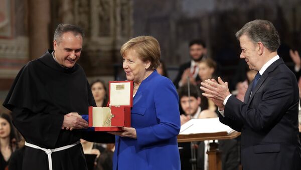 German Chancellor Angela Merkel, center, flanked by Colombian President Juan Manuel Santos, right, receives the St. Francis lamp peace prize by Father Mauro Gambetti during a ceremony inside Assisi's Basilica, Italy, Saturday, May 12, 2018 - Sputnik International