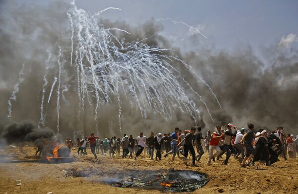 Palestinians run for cover from tear gas during clashes with Israeli security forces near the border between Israel and the Gaza Strip, east of Jabalia on May 14, 2018, as Palestinians protest over the inauguration of the US embassy following its controversial move to Jerusalem - Sputnik International