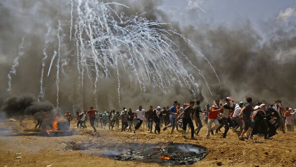 Palestinians run for cover from tear gas during clashes with Israeli security forces near the border between Israel and the Gaza Strip, east of Jabalia on May 14, 2018, as Palestinians protest over the inauguration of the US embassy following its controversial move to Jerusalem - Sputnik International