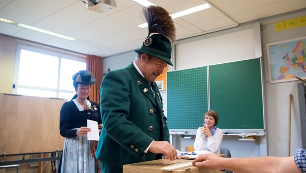 A man and a woman in traditional Bavarian dresses cast their ballots at a polling station in Unterwoessen near Rosenheim, southern Germany, during general elections on September 24, 2017 - Sputnik International
