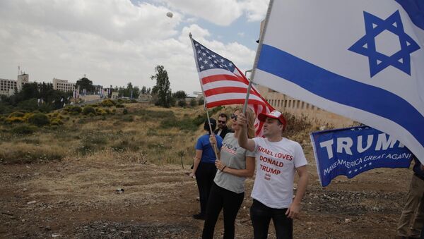 Israelis hold American and Israeli flags with the new U.S. embassy in the background in Jerusalem, Monday, May 14, 2018 - Sputnik International