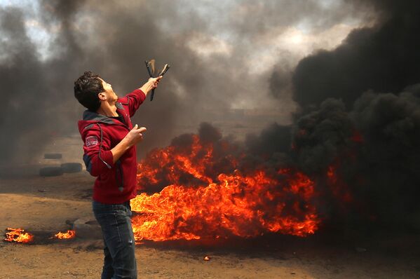 A Palestinian man uses a slingshot during clashes with Israeli forces along the border with the Gaza strip east of Khan Yunis on May 14, 2018, as Palestinians protest over the inauguration of the US embassy following its controversial move to Jerusalem - Sputnik International