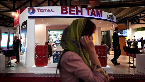A South Korean businesswoman speaks on her mobile phone in front of the stand of French oil and gas company Total, at Iran's annual International Oil, Gas, Refining & Petrochemical Exhibition in Tehran, on May 6, 2014 - Sputnik International