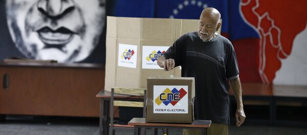With an image of the late Venezuelan President Hugo Chavez behind him a Venezuelan citizen casts his vote at a polling station during the presidential election in Caracas, Venezuela, May 20, 2018 With an image of the late Venezuelan President Hugo Chavez behind him a Venezuelan citizen casts his vote at a polling station during the presidential election in Caracas, Venezuela, May 20, 2018 - Sputnik International