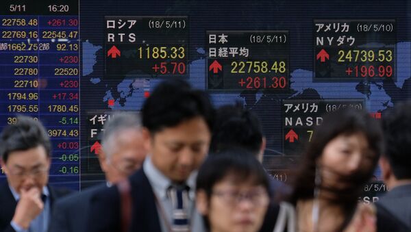 Pedestrians walk past a stock indicator showing share prices of the Tokyo Stock Exchange (top-C) and other overseas stock markets in Tokyo on May 11, 2018 - Sputnik International