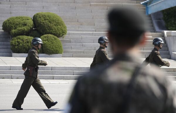 In this April 18, 2018 photo, North Korean soldiers march as a South Korean soldier, center, stands guard during a press tour at the border village of Panmunjom in the Demilitarized Zone, South Korea In this April 18, 2018 photo, North Korean soldiers march as a South Korean soldier, center, stands guard during a press tour at the border village of Panmunjom in the Demilitarized Zone, South Korea - Sputnik International