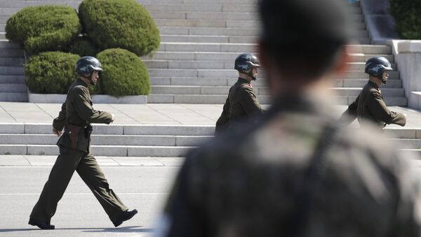 In this April 18, 2018 photo, North Korean soldiers march as a South Korean soldier, center, stands guard during a press tour at the border village of Panmunjom in the Demilitarized Zone, South Korea - Sputnik International