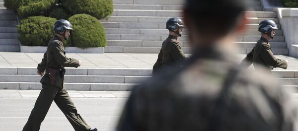 In this April 18, 2018 photo, North Korean soldiers march as a South Korean soldier, center, stands guard during a press tour at the border village of Panmunjom in the Demilitarized Zone, South Korea In this April 18, 2018 photo, North Korean soldiers march as a South Korean soldier, center, stands guard during a press tour at the border village of Panmunjom in the Demilitarized Zone, South Korea - Sputnik International