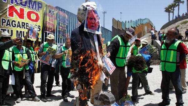 Demonstrators burn an effigy depicting U.S. President Donald Trump during a protest against the immigration policies of Trump's government near the border fence between Mexico and the U.S., in Tijuana, Mexico May 10, 2018 - Sputnik International