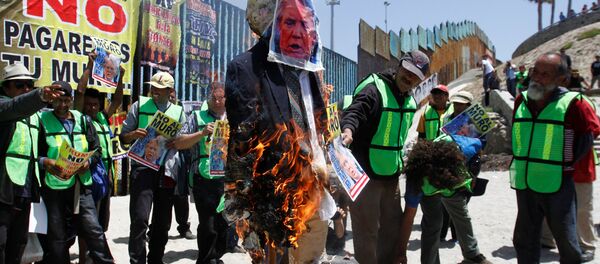 Demonstrators burn an effigy depicting U.S. President Donald Trump during a protest against the immigration policies of Trump's government near the border fence between Mexico and the U.S., in Tijuana, Mexico May 10, 2018 - Sputnik International