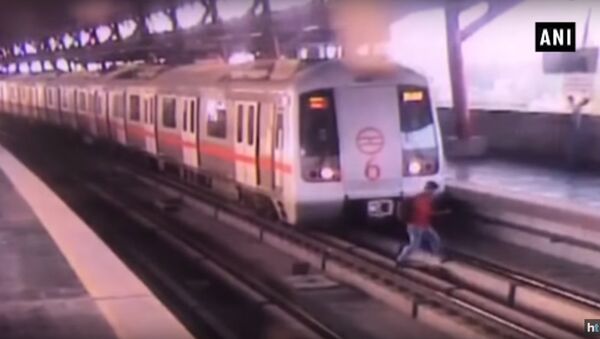 Watch video: Man crosses tracks at Delhi Metro station as train starts moving - Sputnik International