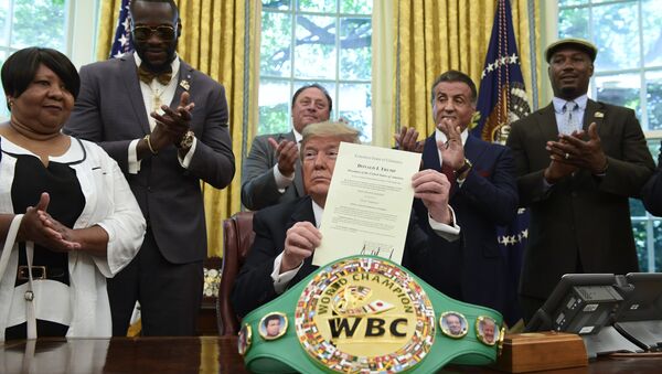 President Trump holds up the pardon as Deontay Wilder (left) and Lennox Lewis (right) applaud - Sputnik International