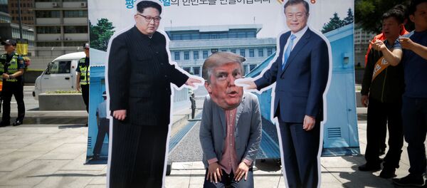 A man wearing a mask of U.S. President Donald Trump kneels down between cutouts of North Korean leader Kim Jong Un and South Korean President Moon Jae-in during an anti-U.S. President Donald Trump rally near U.S. embassy in Seoul, South Korea, May 25, 2018 - Sputnik International