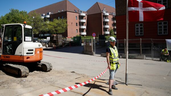 A worker stands beside a Danish flag on a construction site of new housing being built next to Mjolnerparken, a housing estate that features on the Danish government's Ghetto List, in Copenhagen, Denmark, May 8, 2018 - Sputnik International