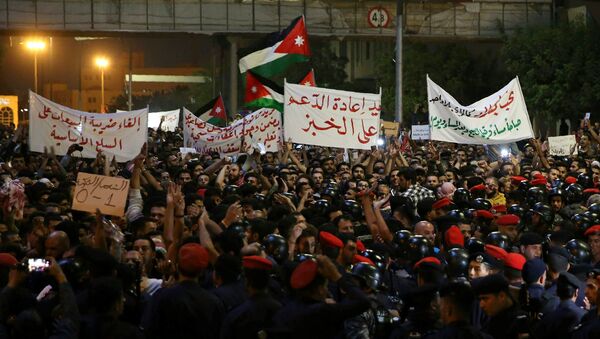 Demonstrators wave flags and hold signs near Jordanian anti-riot police and security forces during a protest in Amman, Jordan, near the prime minister's office on June 4, 2018 - Sputnik International