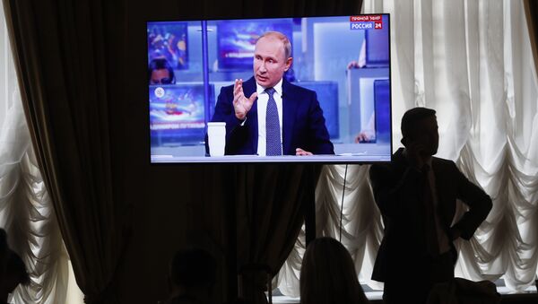 A journalist speaks on the phone while Russian President Vladimir Putin gestures answering a question during his annual call-in show in Moscow, Russia, Thursday, June 7, 2018 - Sputnik International