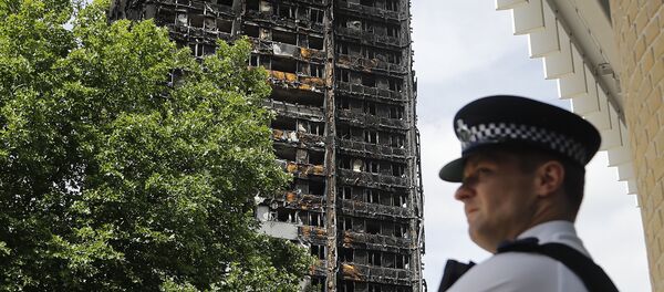 A police officer stands near to the burnt Grenfell Tower apartment building standing testament to the recent fire in London, Friday, June 23, 2017. - Sputnik International