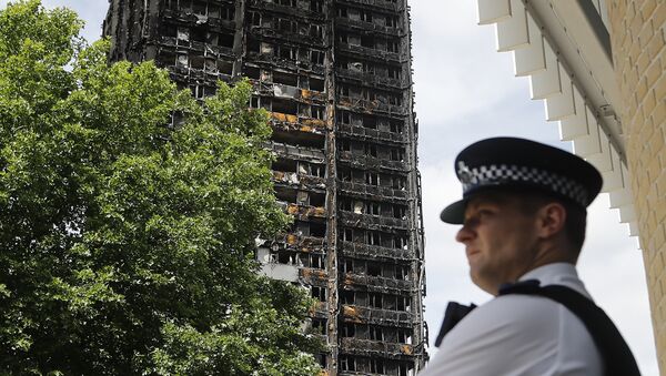 A police officer stands near to the burnt Grenfell Tower apartment building standing testament to the recent fire in London, 23 June 2017.  - Sputnik International