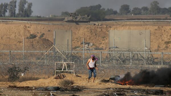 A Palestinian demonstrator stands next to the Israeli fence during a protest marking Naksa, at the Israel-Gaza border in the southern Gaza Strip June 5, 2018 - Sputnik International