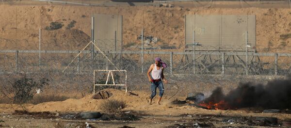 A Palestinian demonstrator stands next to the Israeli fence during a protest marking Naksa, at the Israel-Gaza border in the southern Gaza Strip June 5, 2018 A Palestinian demonstrator stands next to the Israeli fence during a protest marking Naksa, at the Israel-Gaza border in the southern Gaza Strip June 5, 2018 - Sputnik International