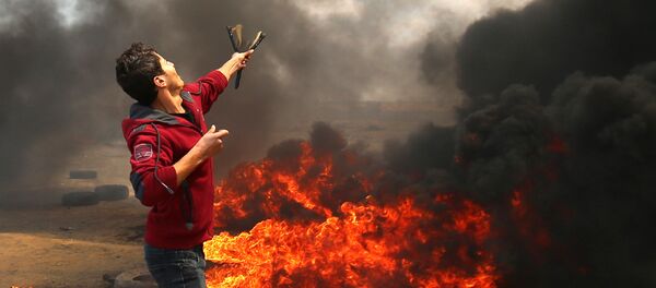 A Palestinian man uses a slingshot during clashes with Israeli forces along the border with the Gaza strip east of Khan Yunis on May 14, 2018, as Palestinians protest over the inauguration of the US embassy following its controversial move to Jerusalem A Palestinian man uses a slingshot during clashes with Israeli forces along the border with the Gaza strip east of Khan Yunis on May 14, 2018, as Palestinians protest over the inauguration of the US embassy following its controversial move to Jerusalem - Sputnik International