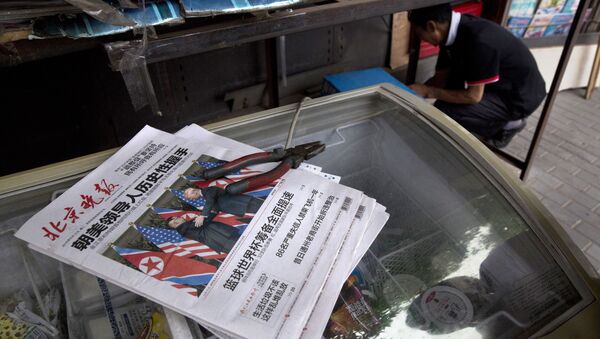 A worker makes repairs at a newspaper stand with front page photos of the meeting in Singapore between U.S. President Donald Trump and North Korean leader Kim Jong Un in Beijing, China, Tuesday, June 12, 2018 - Sputnik International