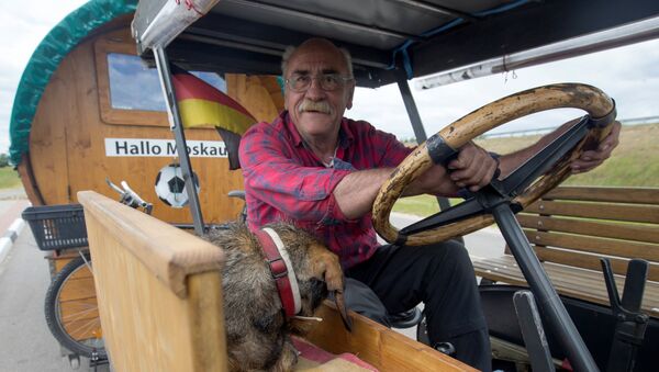 Soccer fan from Pforzheim, Germany, Hubert Wirth, 70, with his dog Hexe, drives his tractor with a trailer to attend the FIFA 2018 World Cup in Russia near the village of Yasen, Belarus June 7, 2018 - Sputnik International