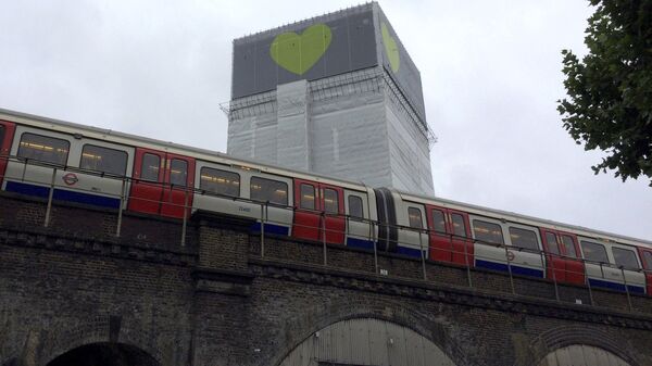 A London Underground train comes to a halt next to Grenfell Tower as a minute's silence is marked on June 14, 2018 - Sputnik International