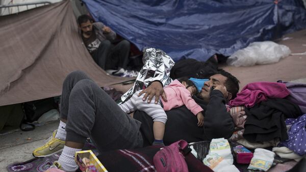 A migrant father and child rest outside the El Chaparral port of entry building at the US-Mexico border in Tijuana, Mexico - Sputnik International
