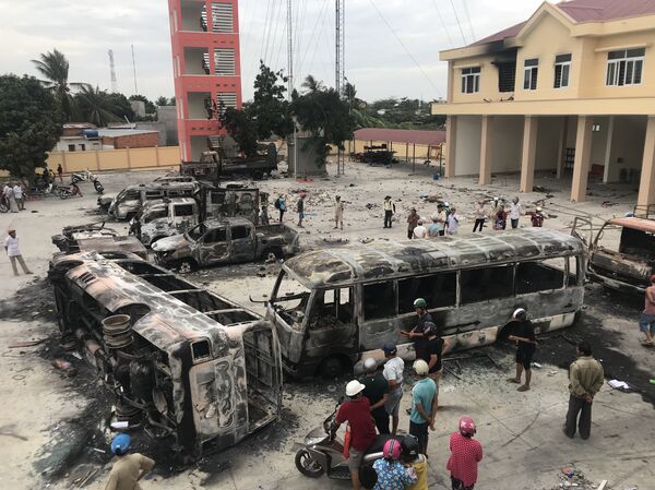 This picture taken on June 12, 2018 shows charred buses at a police station compound in central Binh Thuan province following the June 10 violent protest over a government proposal to issue 99-year-leases in special economic zones. An American citizen is being held in Vietnam for disrupting public order after he joined violent protests over a controverial special economic zone draft law, an official said on June 14 - Sputnik International
