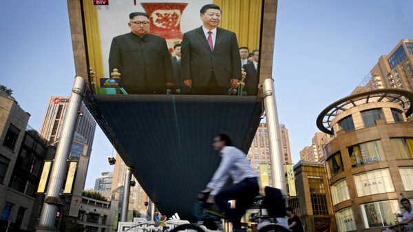 People bicycle past a giant TV screen broadcasting the meeting of North Korean leader Kim Jong Un and Chinese President Xi Jinping during a welcome ceremony at the Great Hall of the People in Beijing, Tuesday, June 19, 2018 - Sputnik International