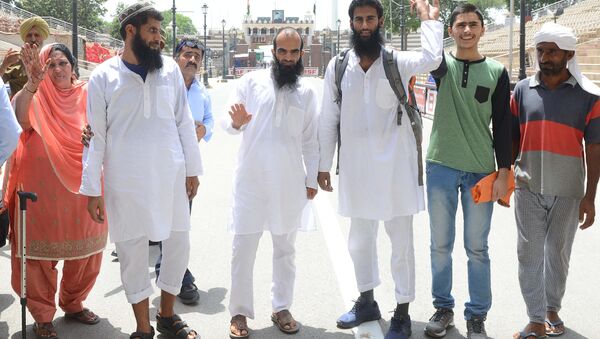 Pakistani former prisoners Nasreen Akhtar (L), Mohammad Yasin Jat (2L), Mohammad Nadeem (C), Akhtar Ul Islam Teeli (3R), Haroon Ali (2R) and Altab(R) wave as they prepare to cross the India-Pakistan border in Wagah, about 35 km from Amritsar on June 19, 2018 - Sputnik International