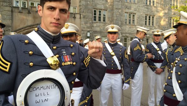 In this May 2016 photo provided by Spenser Rapone, Rapone raises his left fist while displaying a sign inside his hat that reads Communism will win, after graduating from the United States Military Academy at West Point, N.Y. - Sputnik International