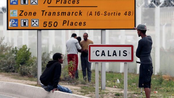 Migrants stand near a city sign along a road near the makeshift camp called The New Jungle in Calais, France, August 19, 2015 - Sputnik International